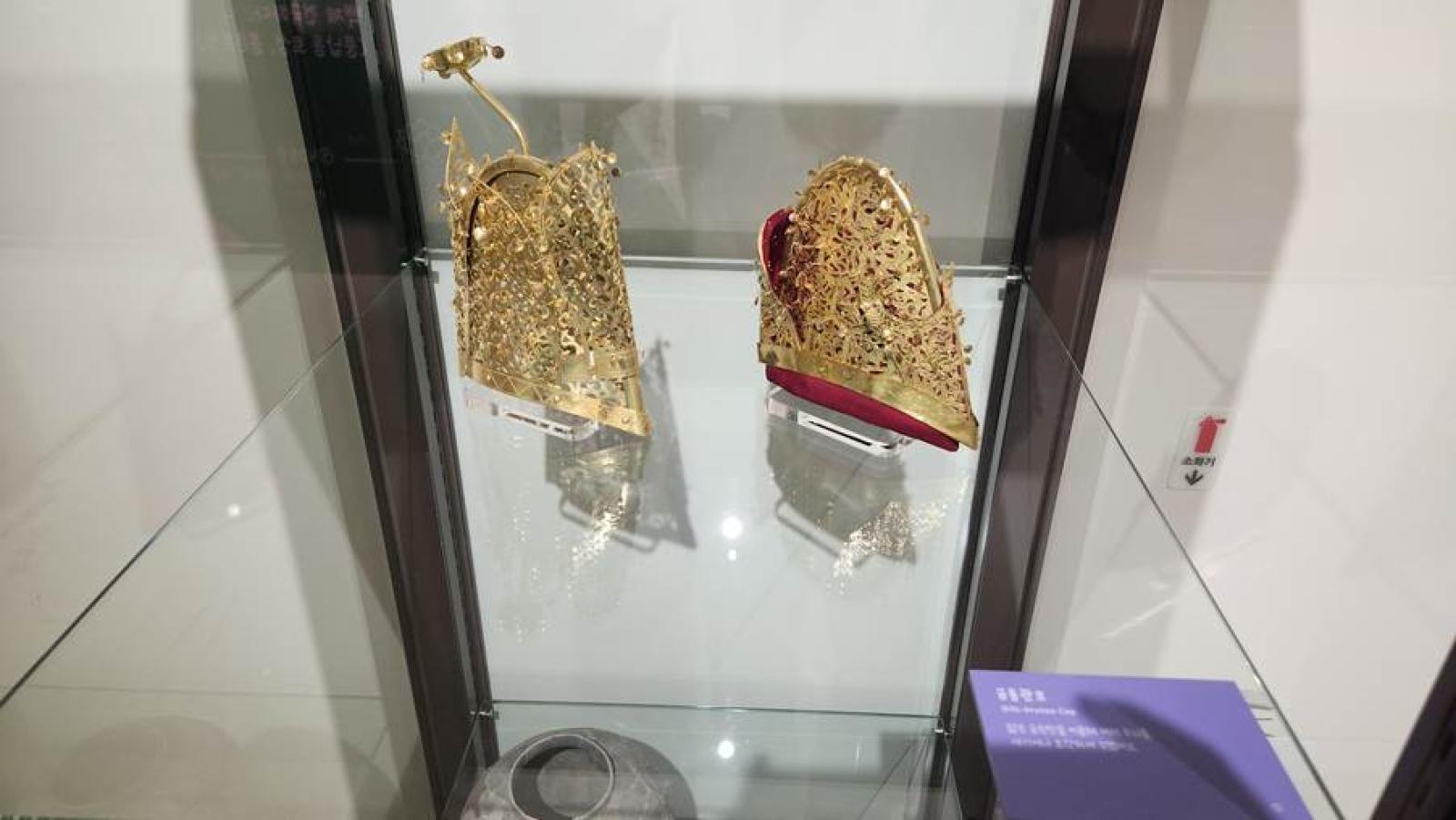 A pair of gold shoes in a glass case AI-generated content may be incorrect.
